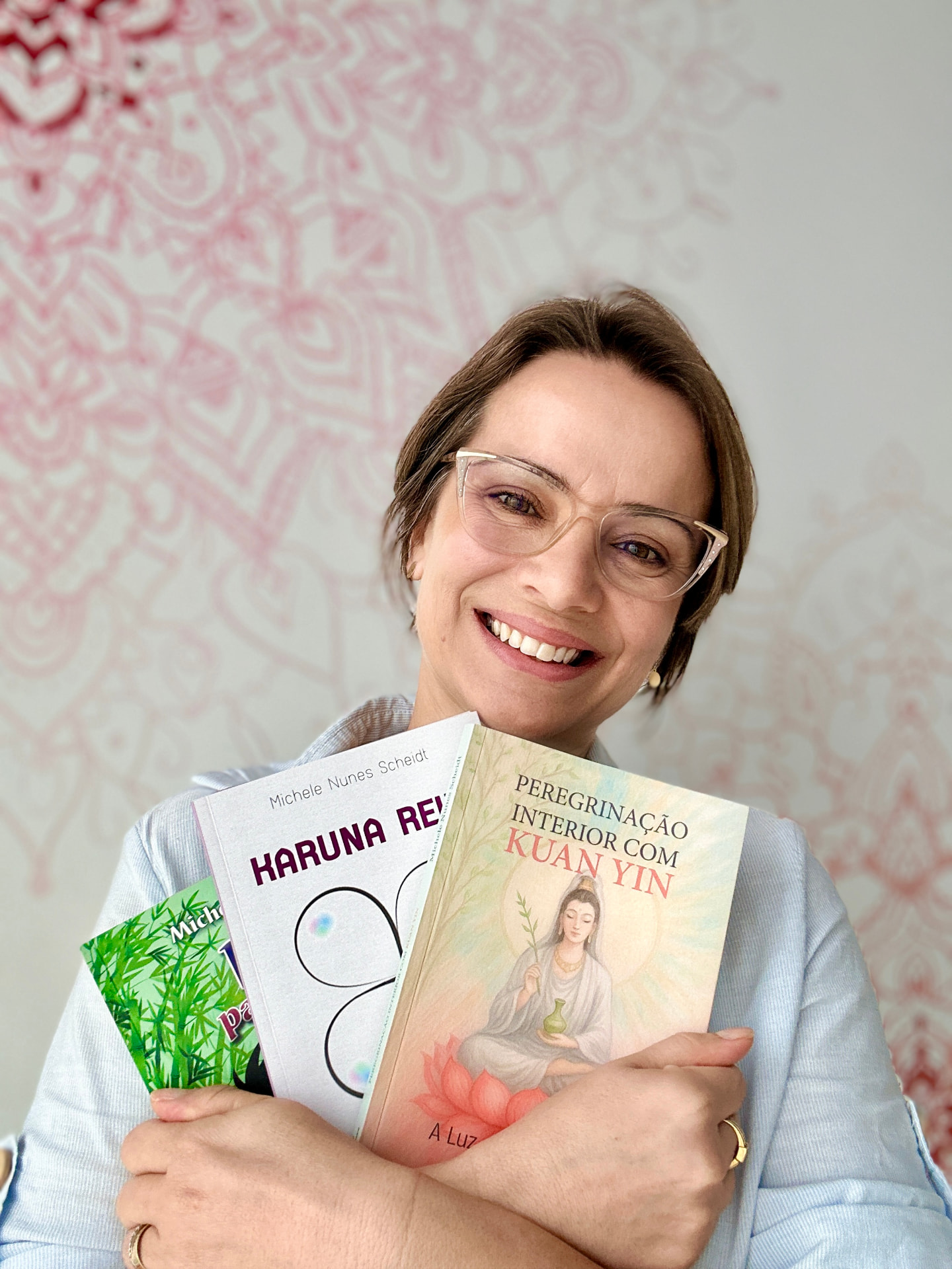 Michele abraçando seus três livros: Reiki para Crianças, Karuna Reiki e Peregrinação Interior com Kuan Yin