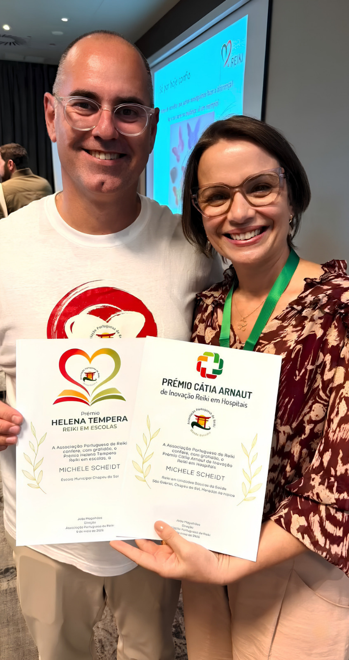 Michele ao lado de outro participante do congresso de Reiki em Portugal, ambos segurando os reconhecimentos