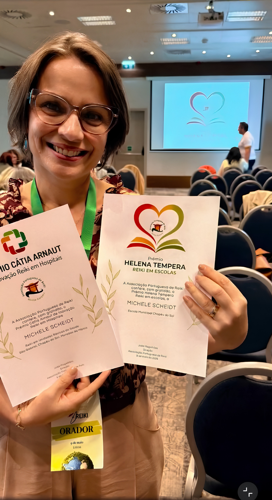Michele segurando os reconhecimentos recebidos no congresso de Reiki em Portugal